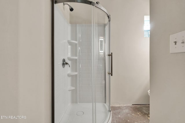 full bathroom featuring a stall shower, unfinished concrete floors, and toilet