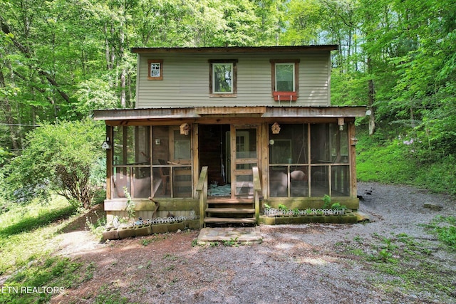 view of front facade with a sunroom and a wooded view