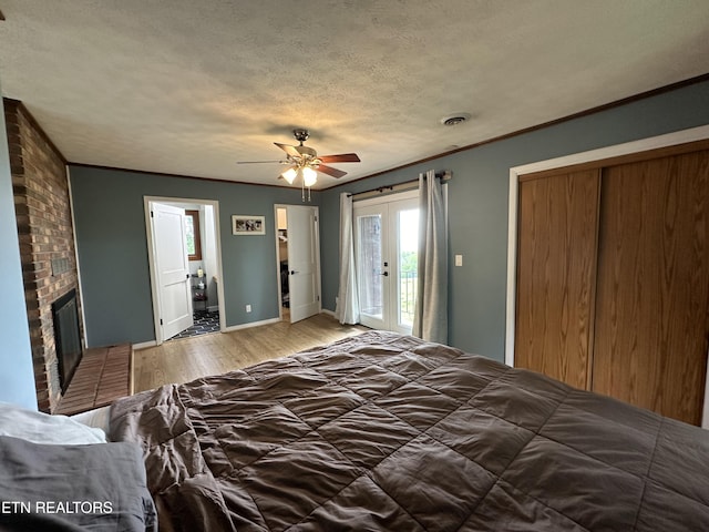 bedroom with crown molding, light wood-type flooring, access to exterior, and a brick fireplace