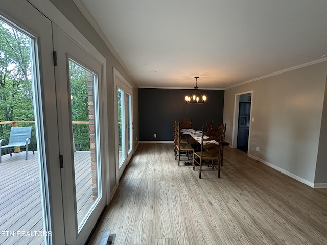 dining space with wood finished floors, ornamental molding, visible vents, an inviting chandelier, and baseboards