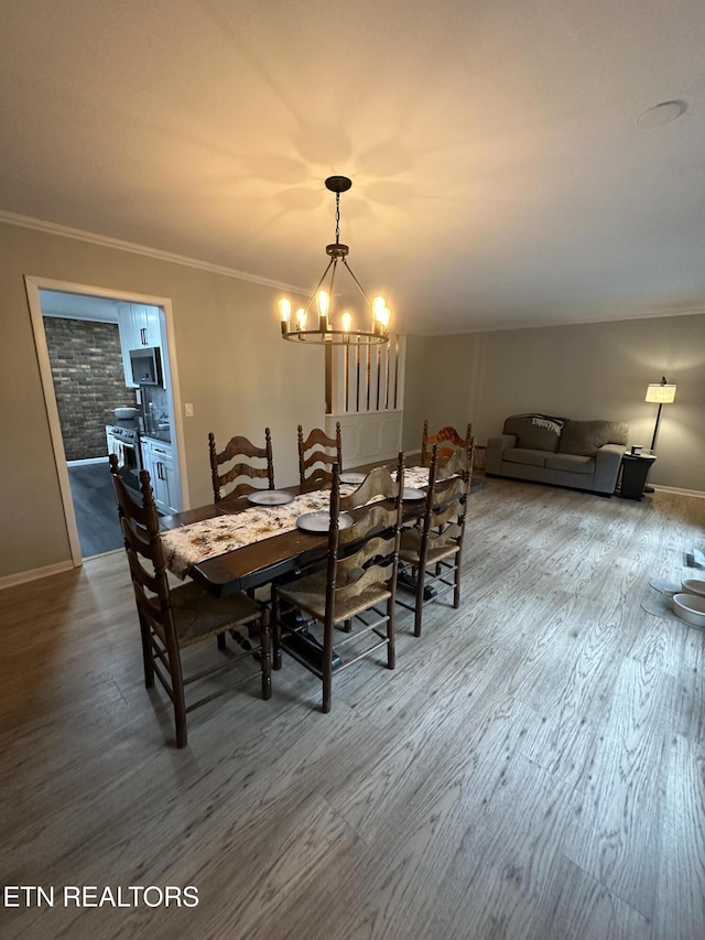 dining space with an inviting chandelier, wood finished floors, baseboards, and ornamental molding