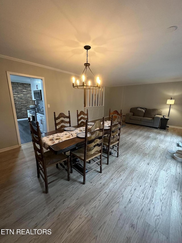 dining area featuring an inviting chandelier, crown molding, baseboards, and wood finished floors