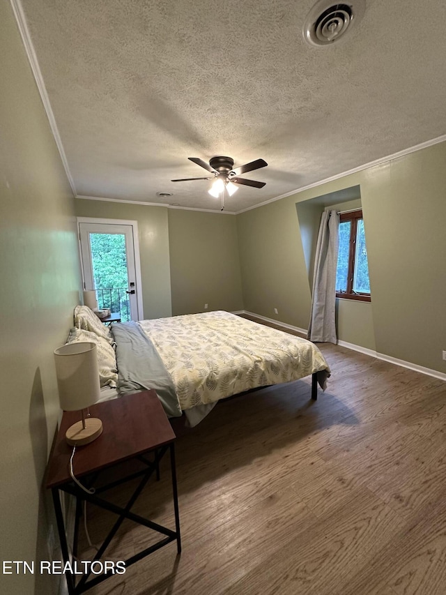 bedroom featuring ceiling fan, a textured ceiling, visible vents, and ornamental molding