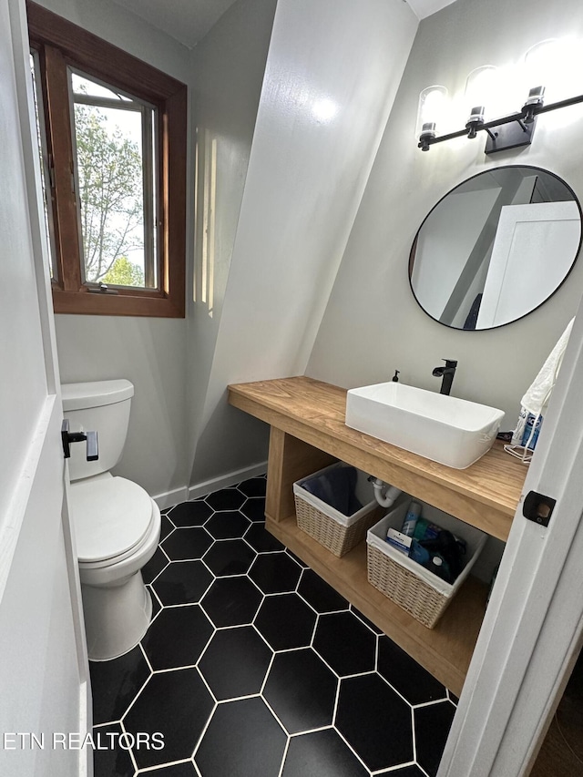 half bathroom featuring a sink, toilet, and baseboards