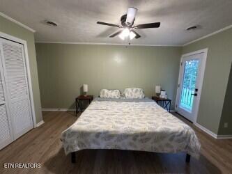 bedroom with a closet, wood finished floors, ornamental molding, ceiling fan, and baseboards