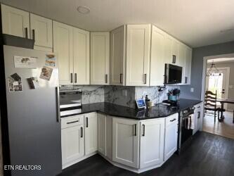 kitchen featuring dark countertops, stainless steel appliances, and dark wood finished floors