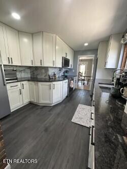 kitchen with stainless steel microwave, recessed lighting, dark wood finished floors, white cabinetry, and backsplash