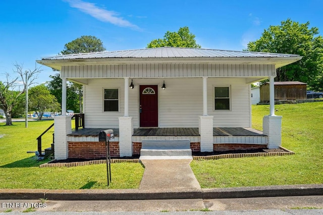 bungalow with metal roof, a porch, and a front lawn