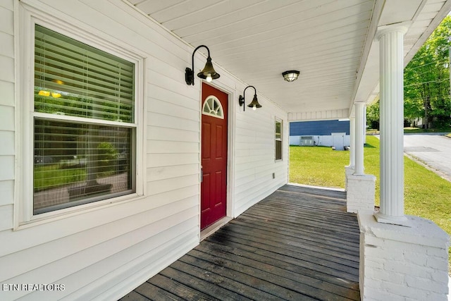 wooden deck featuring a lawn and covered porch