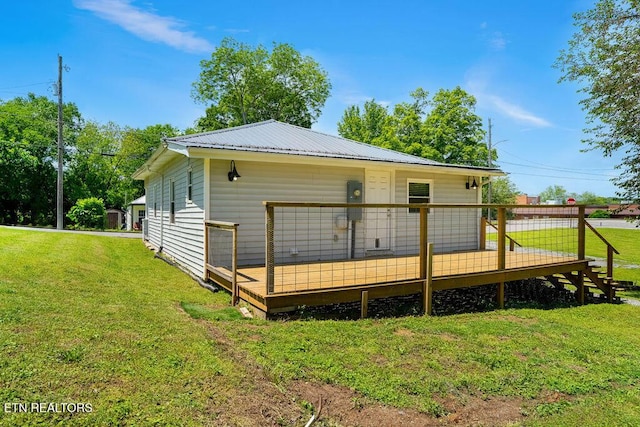 rear view of property featuring a lawn, metal roof, and a wooden deck