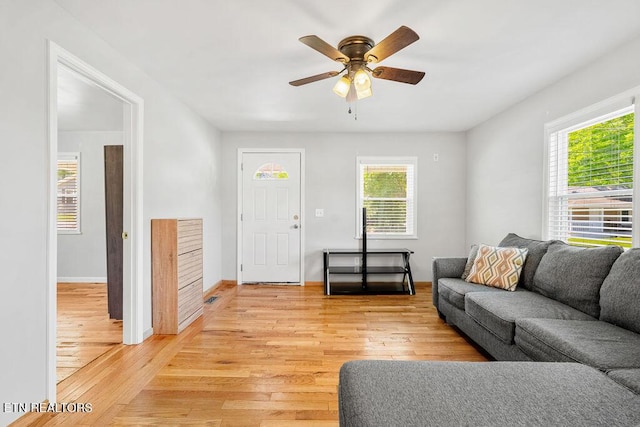 living room with ceiling fan, a wealth of natural light, baseboards, and light wood-type flooring