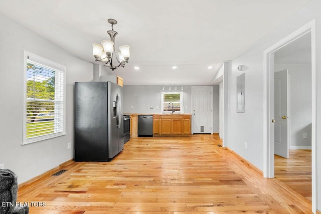 kitchen featuring light wood finished floors, light countertops, stainless steel appliances, and a wealth of natural light