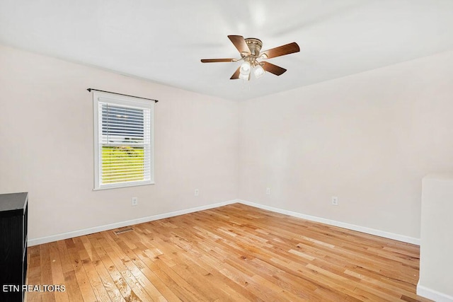 empty room featuring baseboards, light wood-style floors, visible vents, and ceiling fan