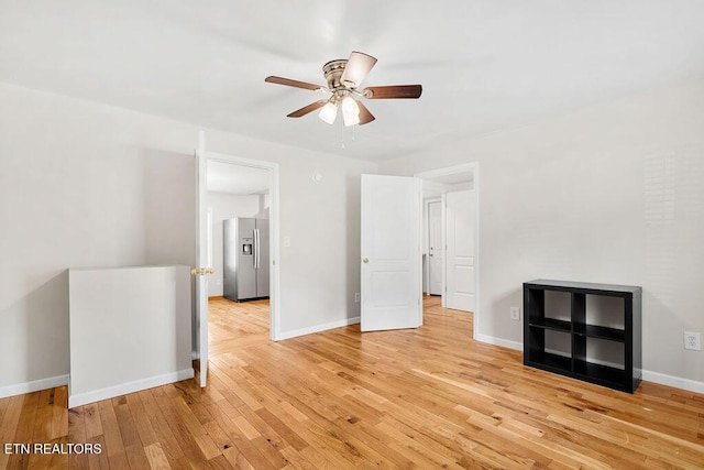 interior space featuring light wood-style flooring, stainless steel fridge with ice dispenser, baseboards, and a ceiling fan