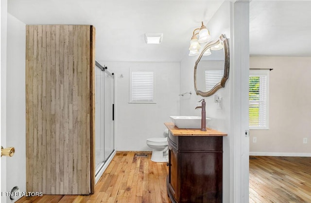 bathroom with toilet, a stall shower, wood-type flooring, baseboards, and vanity