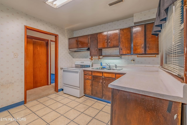kitchen featuring white range with electric cooktop, wallpapered walls, a sink, light countertops, and light tile patterned floors