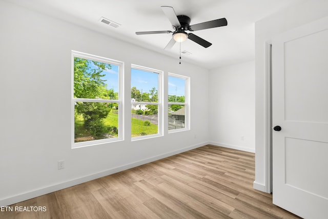 empty room with a ceiling fan, light wood-style floors, visible vents, and baseboards