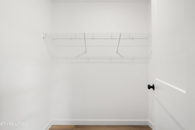 walk in closet with wood finished floors
