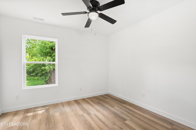 spare room with light wood-type flooring, visible vents, baseboards, and a ceiling fan