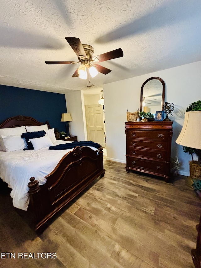 bedroom featuring ceiling fan, a textured ceiling, baseboards, and wood finished floors