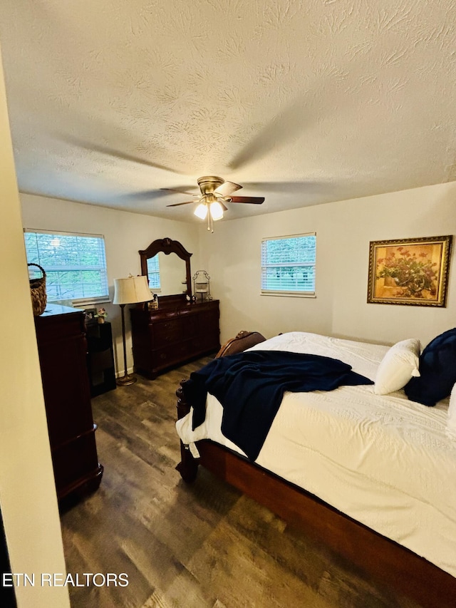 bedroom with a textured ceiling, dark wood-style flooring, and ceiling fan