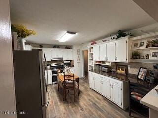 kitchen with open shelves, stainless steel appliances, wood finished floors, and white cabinets