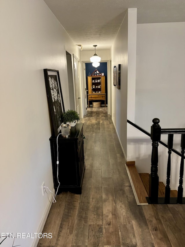 corridor featuring baseboards and dark wood-style floors