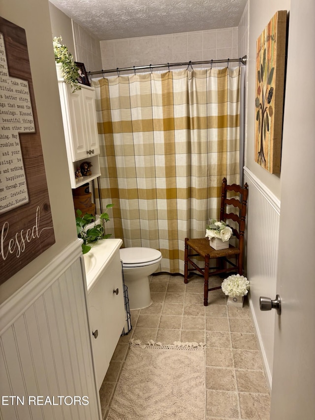 full bath with toilet, vanity, a textured ceiling, and curtained shower