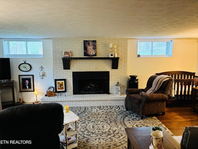 living room with a fireplace, a textured ceiling, and wood finished floors