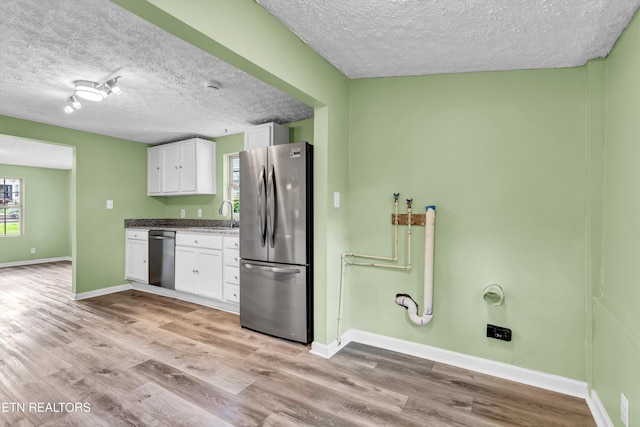 2423 Mccroskey Ave, Knoxville, TN 37917 - kitchen with stainless steel appliances, a textured ceiling, white cabinets, light wood-style flooring, and baseboards