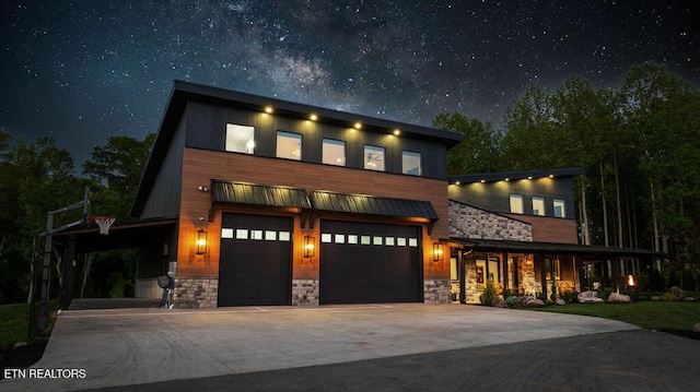 modern home featuring concrete driveway, a garage, and stone siding