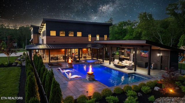 back of house at night featuring an outdoor hangout area, a patio area, and fence