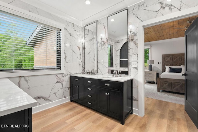 full bath with double vanity, wood finished floors, a sink, ensuite bathroom, and ornamental molding