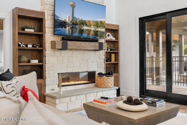 living area with built in shelves, a fireplace, and wood finished floors