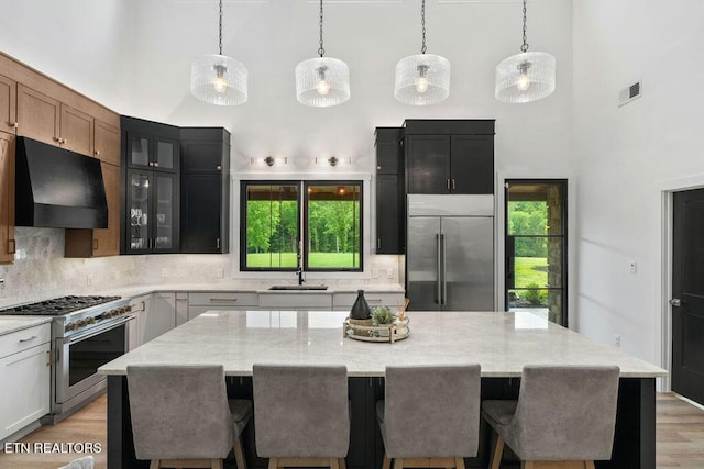 kitchen featuring ventilation hood, a high ceiling, high quality appliances, and tasteful backsplash