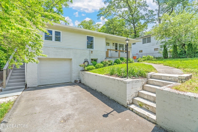 view of front of home featuring stairway, aphalt driveway, a garage, and brick siding