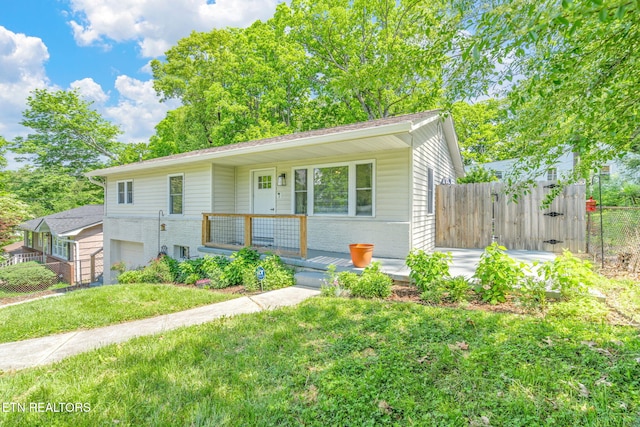 view of front of property with covered porch, brick siding, a front lawn, and fence