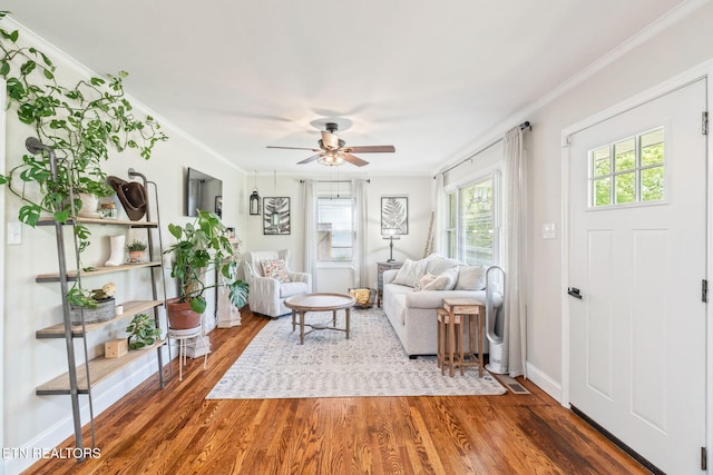 living room featuring baseboards, wood finished floors, a ceiling fan, and ornamental molding