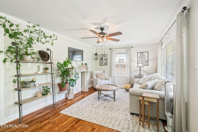 living area with crown molding, baseboards, wood finished floors, and a ceiling fan