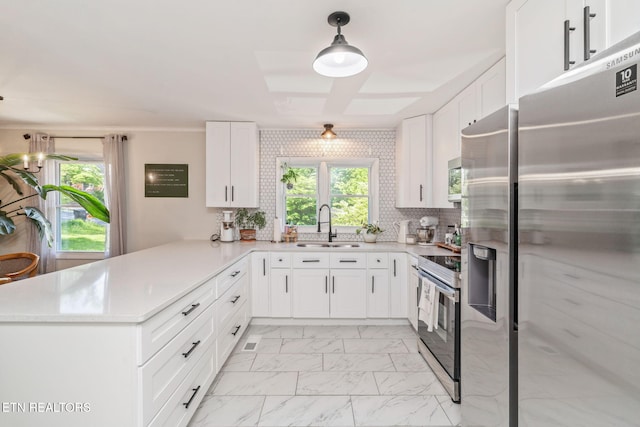 kitchen featuring stainless steel appliances, marble finish floor, a sink, a peninsula, and light countertops