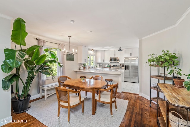 dining room with ornamental molding, a notable chandelier, and wood finished floors