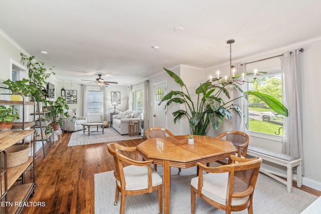 dining area featuring crown molding, ceiling fan with notable chandelier, and wood finished floors