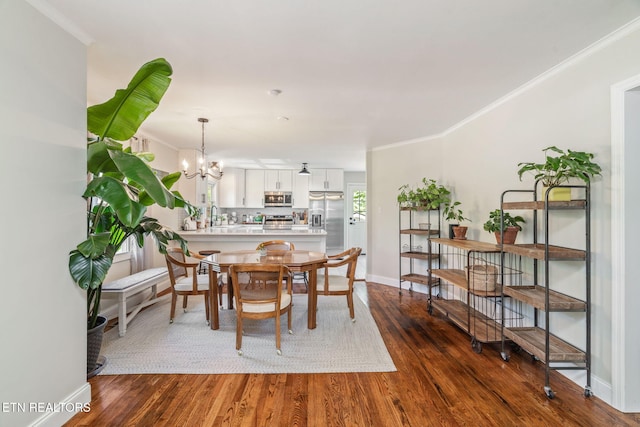 dining room featuring crown molding, a notable chandelier, dark wood-type flooring, and baseboards