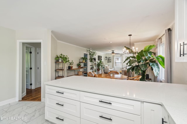 kitchen featuring ceiling fan with notable chandelier, open floor plan, pendant lighting, white cabinetry, and marble finish floor