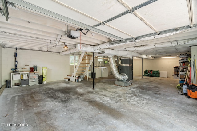 garage with concrete block wall, a garage door opener, and washer and dryer