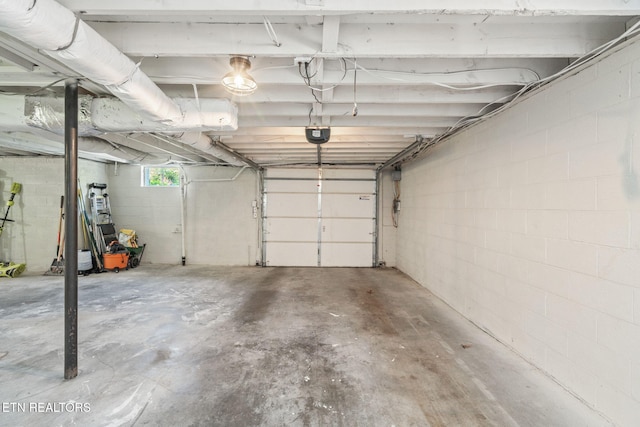 garage featuring concrete block wall and a garage door opener
