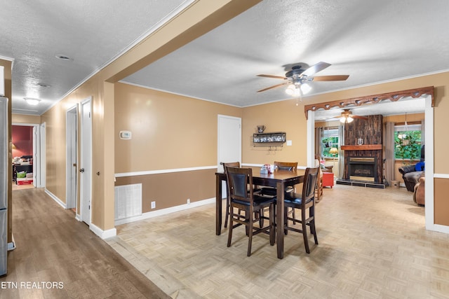 217 Jackson Dr, Harriman, TN 37748 - dining area featuring a textured ceiling, a ceiling fan, a stone fireplace, crown molding, and baseboards