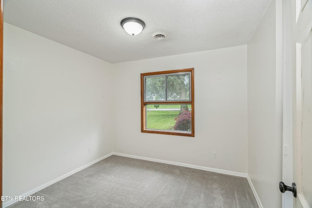 carpeted spare room with a textured ceiling and baseboards