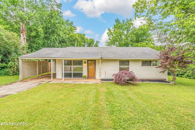 ranch-style house with driveway, a front yard, a carport, and roof with shingles