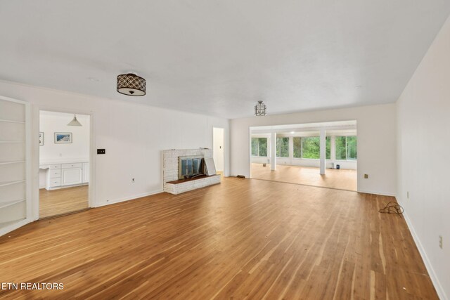 138 Lilac Dr, Lafollette, TN 37766 - unfurnished living room with light wood-style floors, a brick fireplace, and baseboards